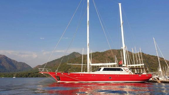 Red yacht Mio Vento in the harbour of Marmaris, surrounded by mountains and clear skies.